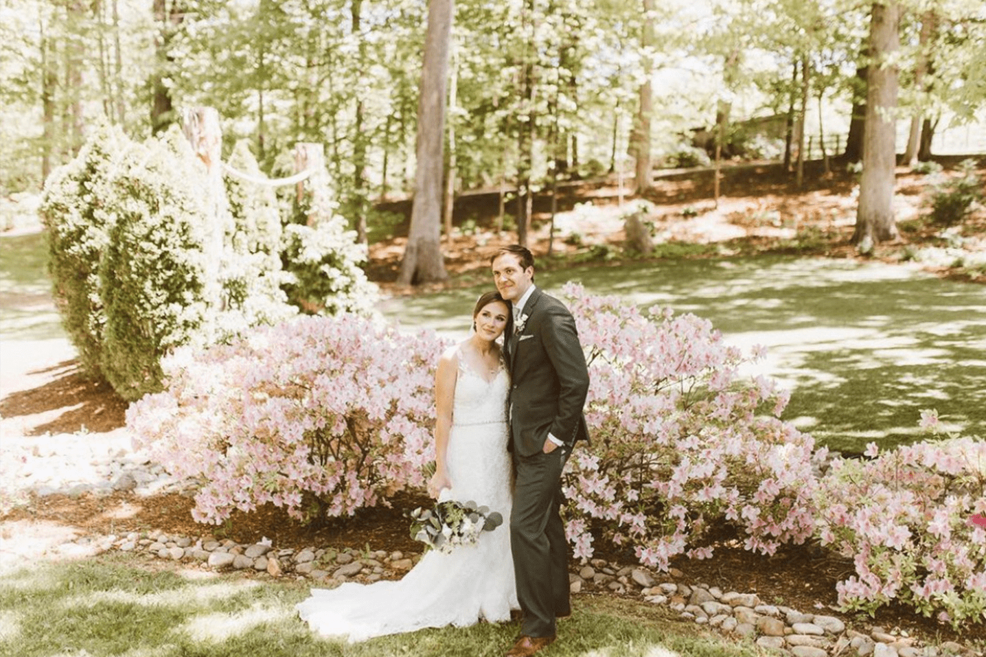 bride and groom posing around pink flowers in The Julianna gardens